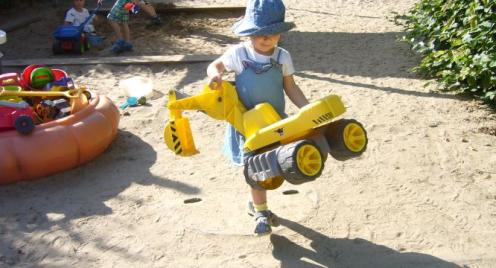 Kind mit Bagger im Sandkasten